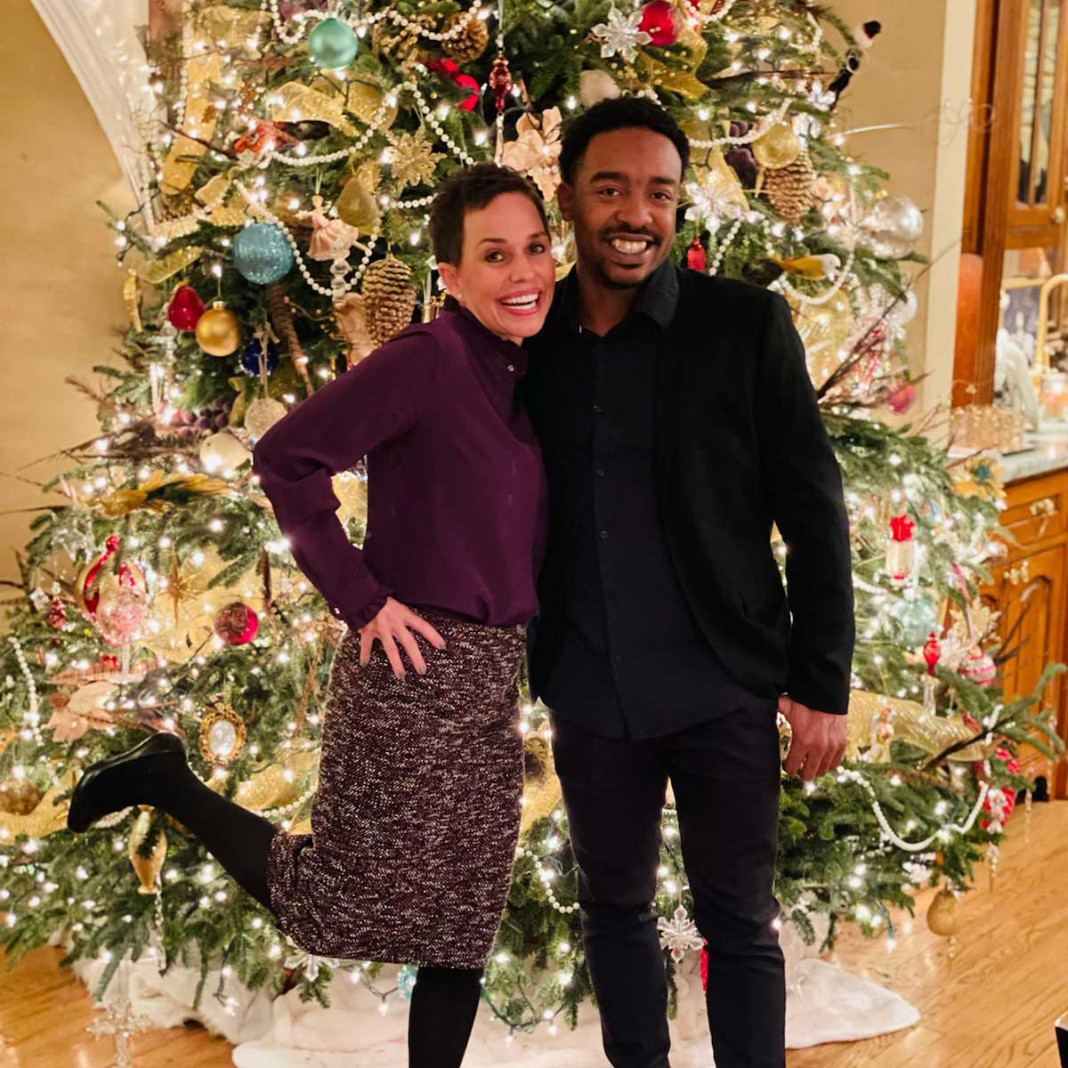 Kim Henderson and Maurice Mouzon Jr. wearing formal attire and posing in front of a Christmas tree