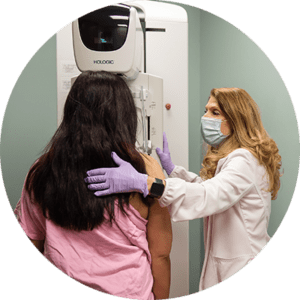Nurse helping woman step towards mammography machine